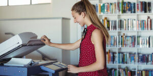 Teacher using a copier in a library
